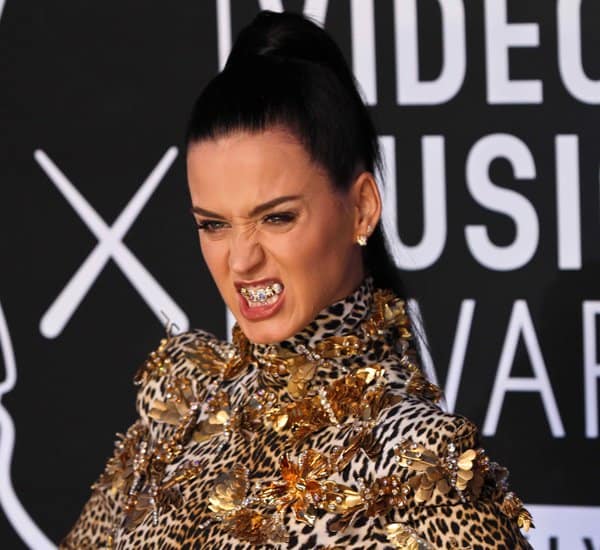 Katy Perry flashes a fierce snarl on the red carpet, playfully showing off her glittering grills and the bold gold embellishments of her Emanuel Ungaro gown