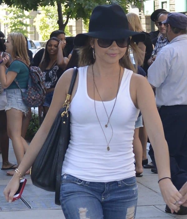 Sarah Hyland sports a stylish fedora hat, paired with a plain white tank top and distressed cropped jeans, while out in Manhattan