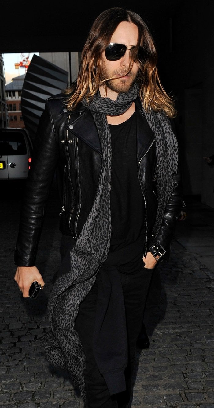 Jared Leto wraps a long leopard print scarf around his neck, adding a unique touch to his all-black outfit