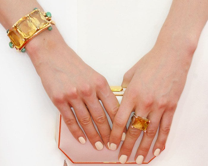 Taylor Schilling shows off her white manicure as she holds a geometric clutch in both hands