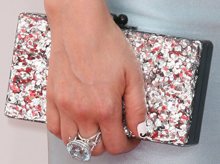 Zooey Deschanel shows off her Chanel cocktail ring — and her quirky mustache-manicure — while holding her Edie Parker clutch