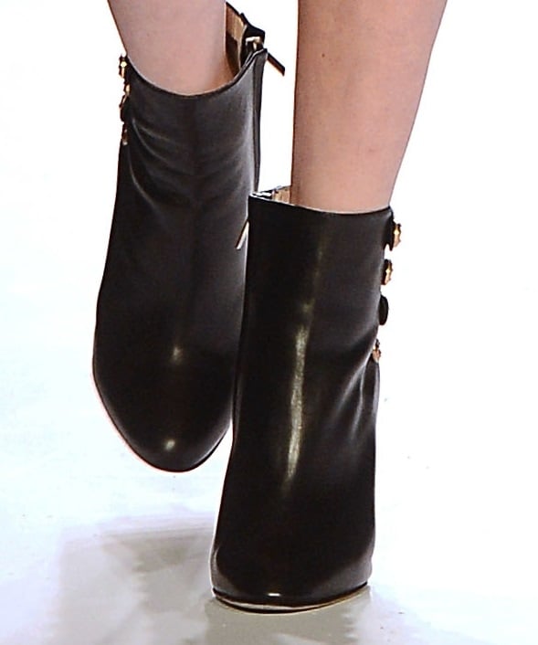 Close-up of Brittany Snow's stylish black ankle booties with gold button detailing