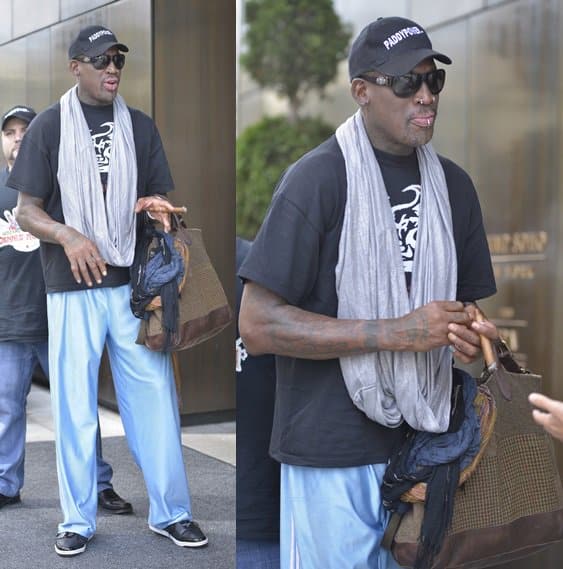 Dennis Rodman makes a fashion statement with a metallic infinity scarf and a stylishly adorned handbag upon his return from North Korea