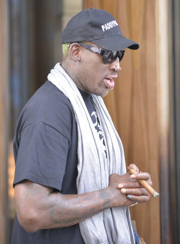 Captured in a moment of unique style, Dennis Rodman pairs a metallic infinity scarf with casual wear and a hint of blue nail polish, showcasing his iconic flair