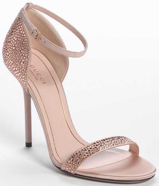 Mixed crystals shimmer with liquid sparkle across the refined restraint of a minimalist, ankle-strap sandal