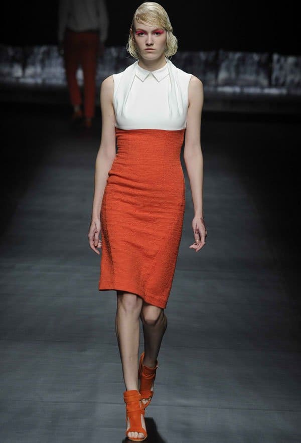 Model in an orange dress with fabric manipulation details by A Degree Fahrenheit