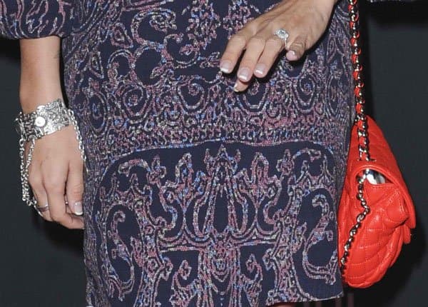 Close-up of Ashley Tisdale's accessories, including a silver bracelet, a red quilted purse, and her engagement ring