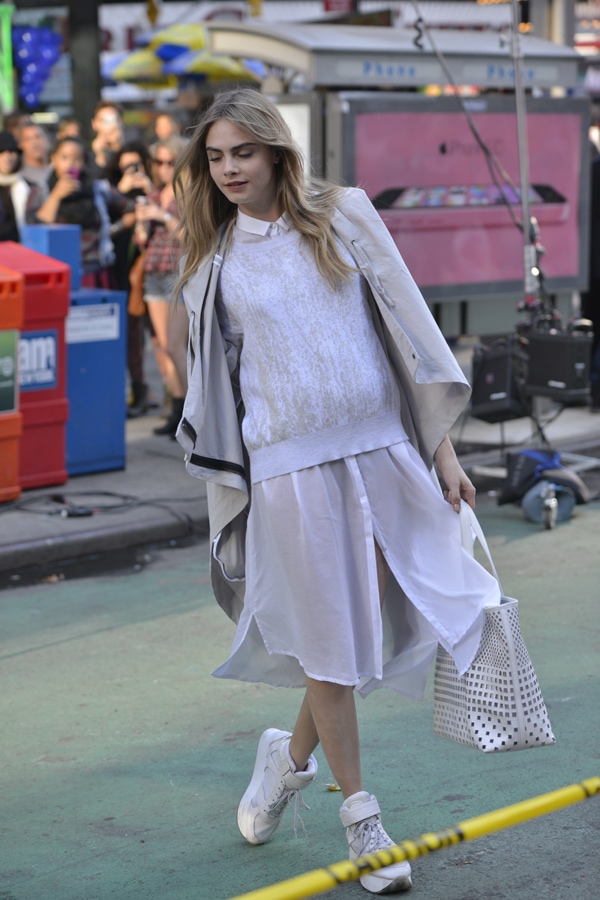 Cara Delevingne stuns in an effortlessly monochromatic DKNY look, pairing a sheer layered skirt with a sleek coat and sporty white high-tops for urban sophistication