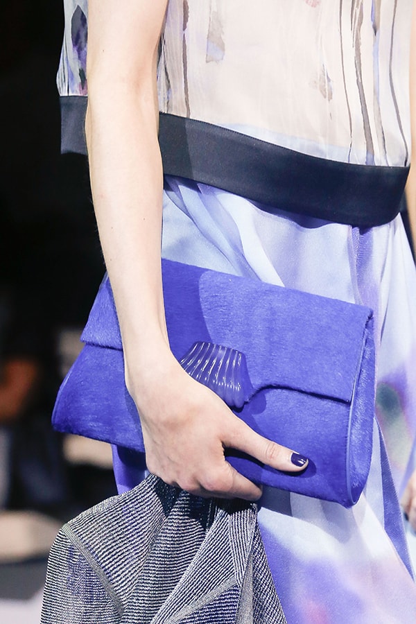 Model holding a vibrant blue Giorgio Armani clutch, paired with a flowy, patterned dress
