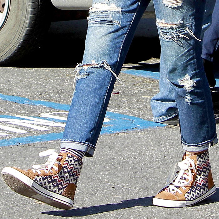 Gwen Stefani elevates her style with a high-top sneaker adorned in chunky knit insets and a luxuriously warm genuine sheepskin lining, exuding both comfort and vibrant charm