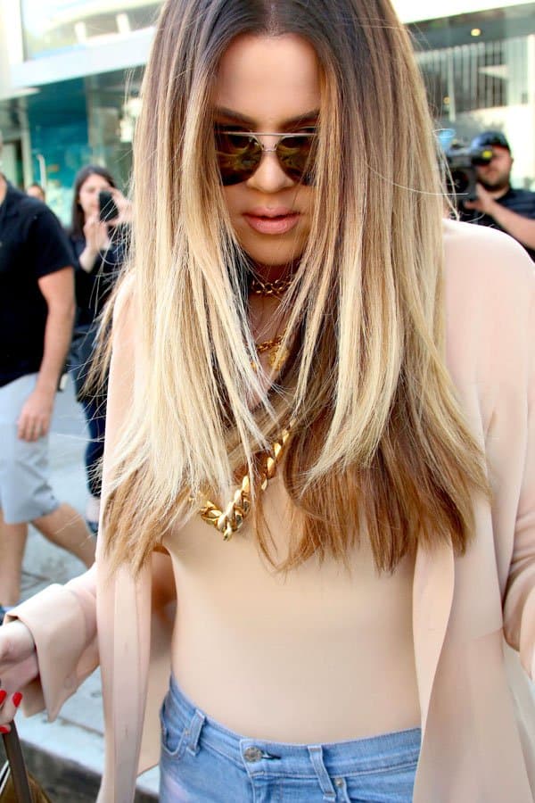 Khloé Kardashian flaunting her chic style with a beige top and oversized sunglasses, complemented by gold accessories during her shopping trip at Kitson