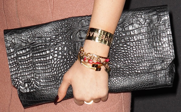 Kylie Jenner holds a metallic clutch and shows off her stack of bracelets