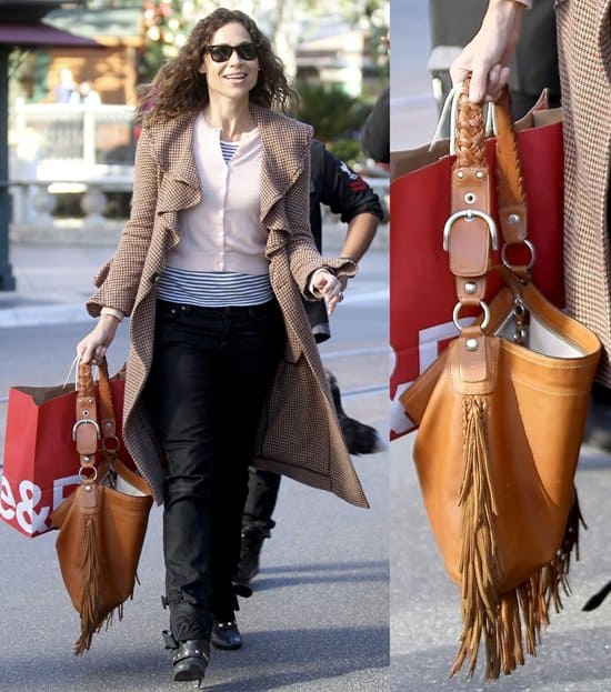 Minnie Driver exudes effortless street style in a houndstooth ruffled coat, striped top, black jeans, ankle boots, and a statement caramel fringe handbag while out shopping