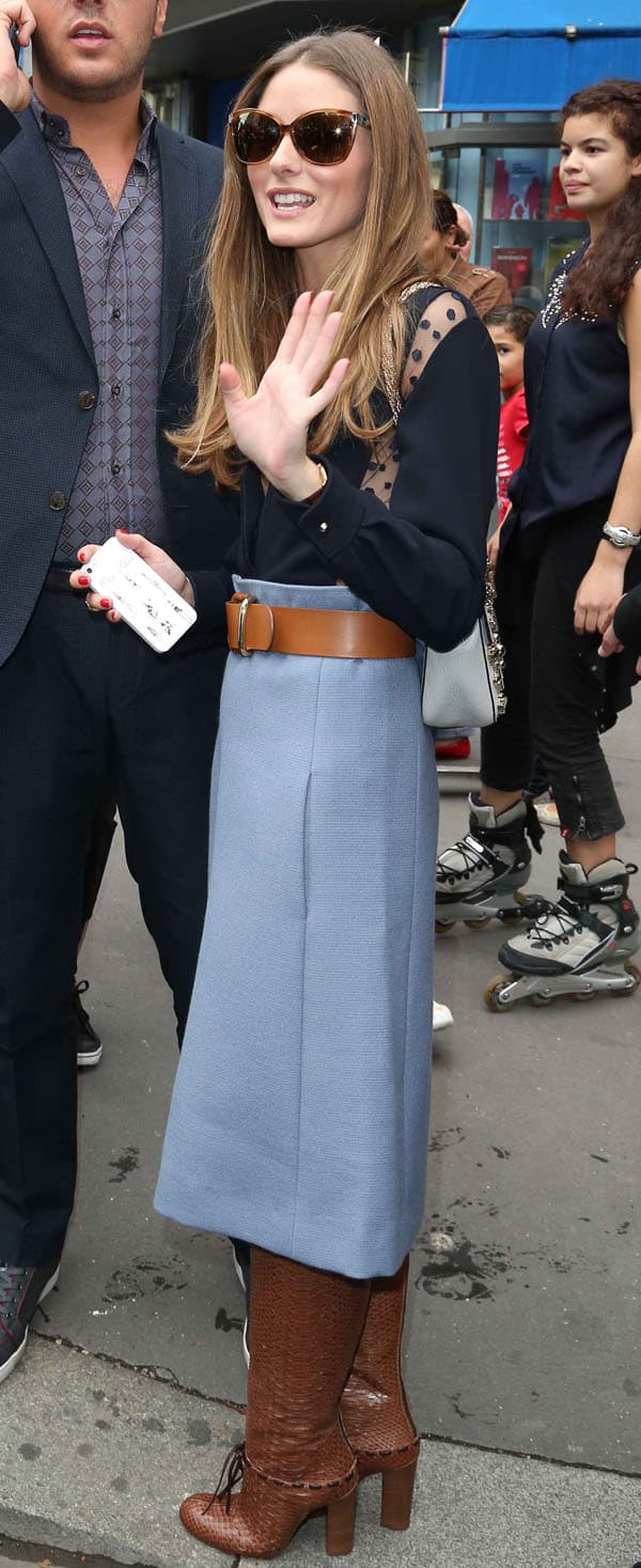 Olivia Palermo styled her black sheer polka dot panel blouse with brown boots and a blue midi skirt