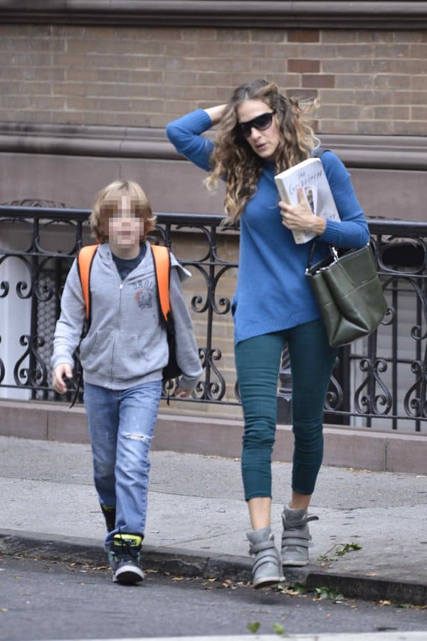 Sarah Jessica Parker keeps it casual and stylish in green cropped pants, a blue sweater, and gray wedge sneakers while walking her child to school