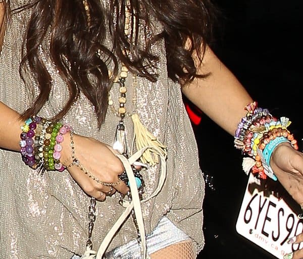 A close-up of Vanessa Hudgens' eclectic mix of colorful beaded bracelets, tassel necklaces, and a unique finger chain bracelet, showcasing her signature bohemian style