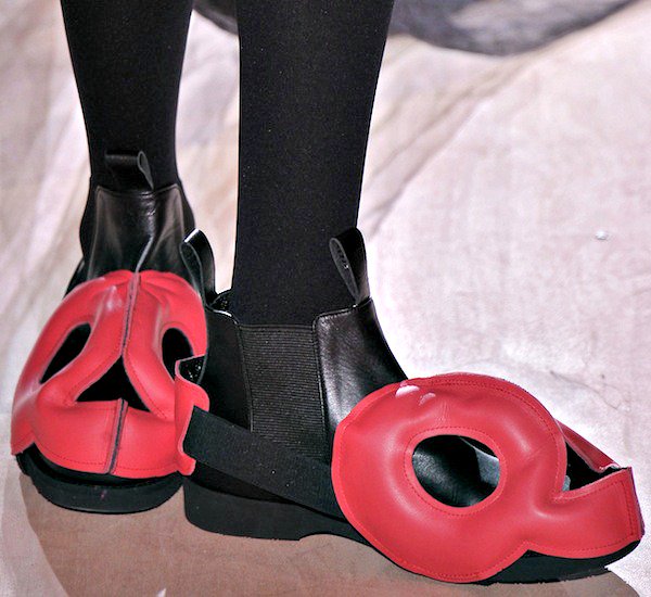 Black Chelsea boots with striking red sculptural cutouts and bold circular accents