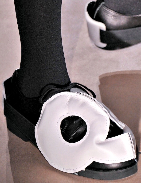 Black open-toe shoes with a bold white circular cut-out design, merging playful geometry with edgy avant-garde aesthetics