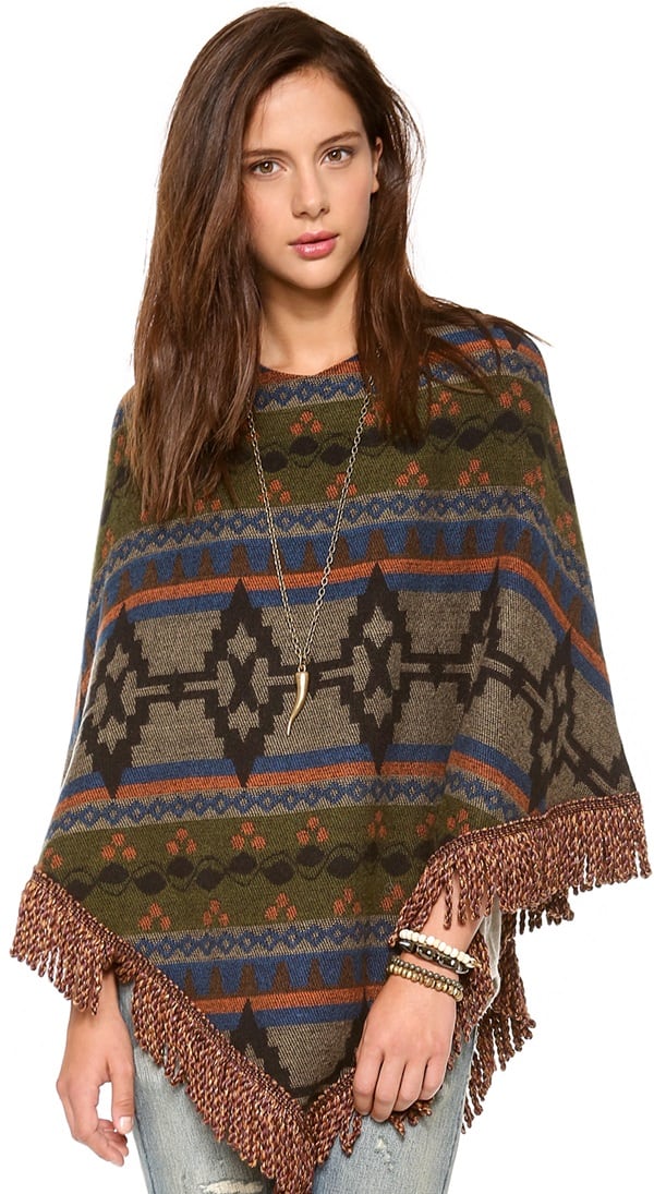 This poncho features a tribal-inspired pattern and cabled fringe at the hem