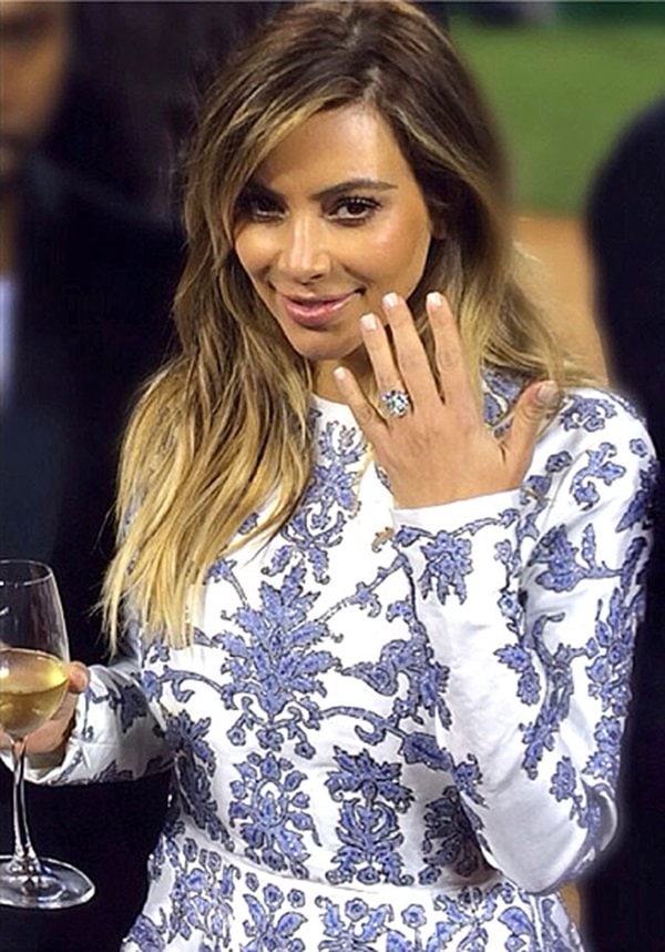 Kim Kardashian's engagement ring features a 15 carat cushion cut diamond in a prong setting and a diamond paved band