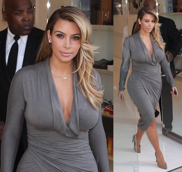 Kim Kardashian flaunting her curves in a fitted gray long-sleeved wrap dress with a plunging neckline