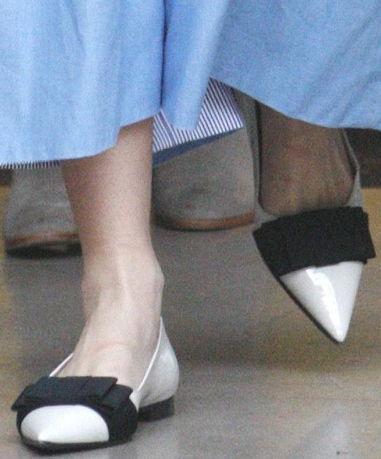 Miranda Kerr steps out in chic white patent leather flats by Miu Miu, featuring a pointed toe and black grosgrain bow detailing for a polished look