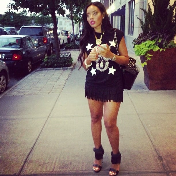 Angela Simmons styles a pair of black MIA Limited Edition "Rocco" sandals with a fringe miniskirt and embellished shirt