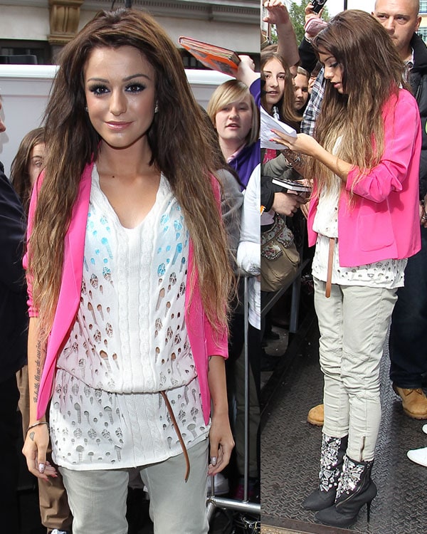 Cher Lloyd effortlessly combines edgy and chic, rocking a bold pink blazer, a cozy white knit top, and floral ankle boots while greeting fans
