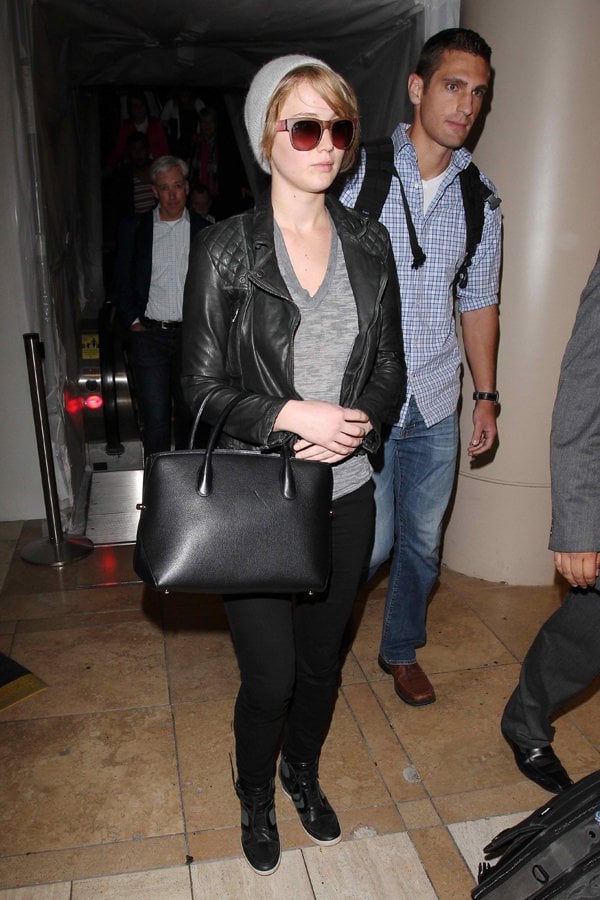 Jennifer Lawrence exudes effortless style at LAX, pairing an AllSaints leather jacket with Adidas high-tops despite looking weary from her travels