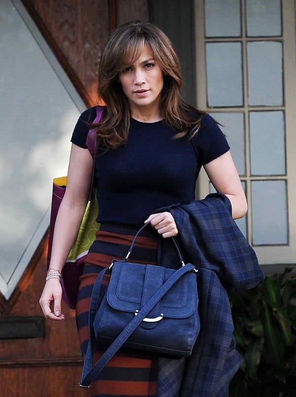 Dressed in a fitted knitted top, striped pencil skirt, and carrying a stylish navy handbag, Jennifer Lopez proves that chic sophistication transcends age