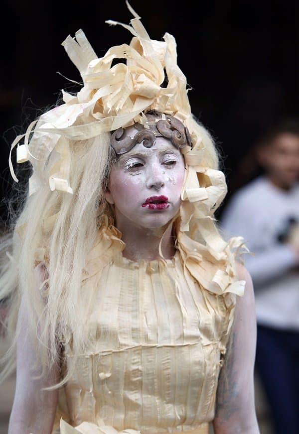 Lady Gaga in a dress made of paper-thin strips of shaved wood, with dramatic makeup and headpiece, leaving her hotel in London