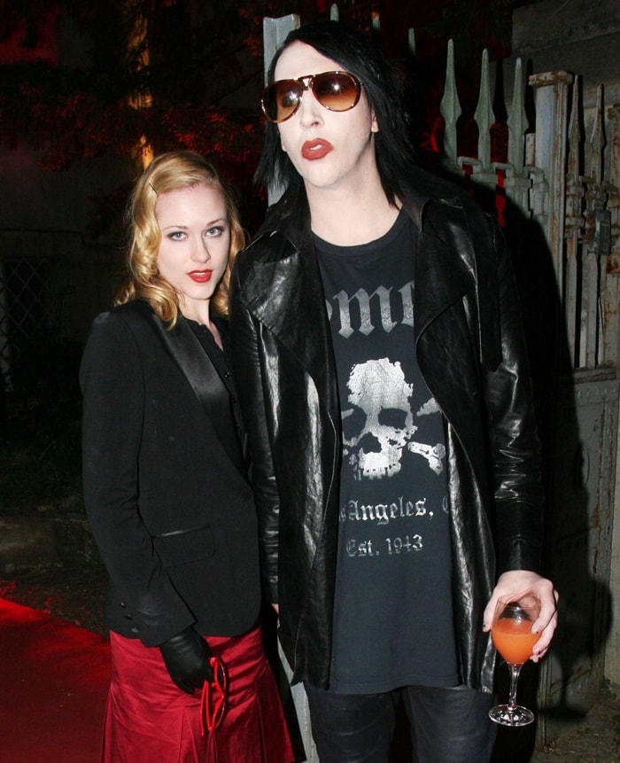 Evan Rachel Wood channels old Hollywood glam in a red satin skirt, tailored black blazer, and leather gloves, while Marilyn Manson embraces his signature gothic edge in a skull-print tee and long leather coat at his album listening party
