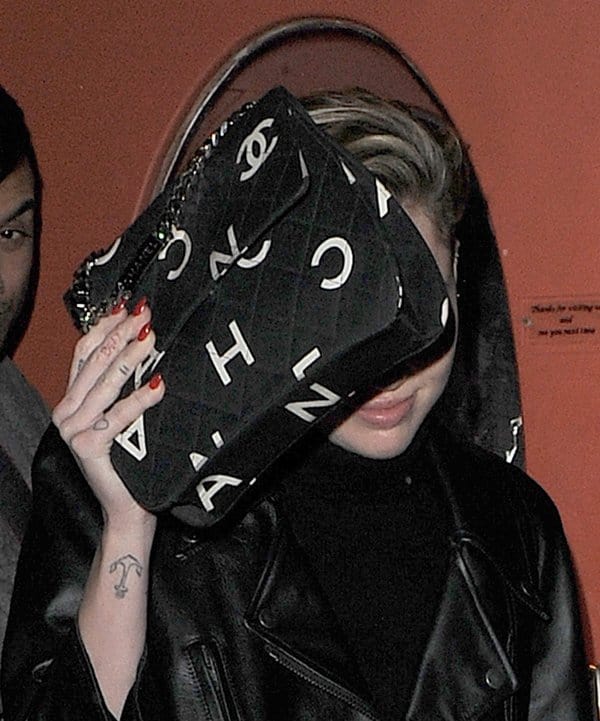 Miley Cyrus hiding her face with a Chanel bag