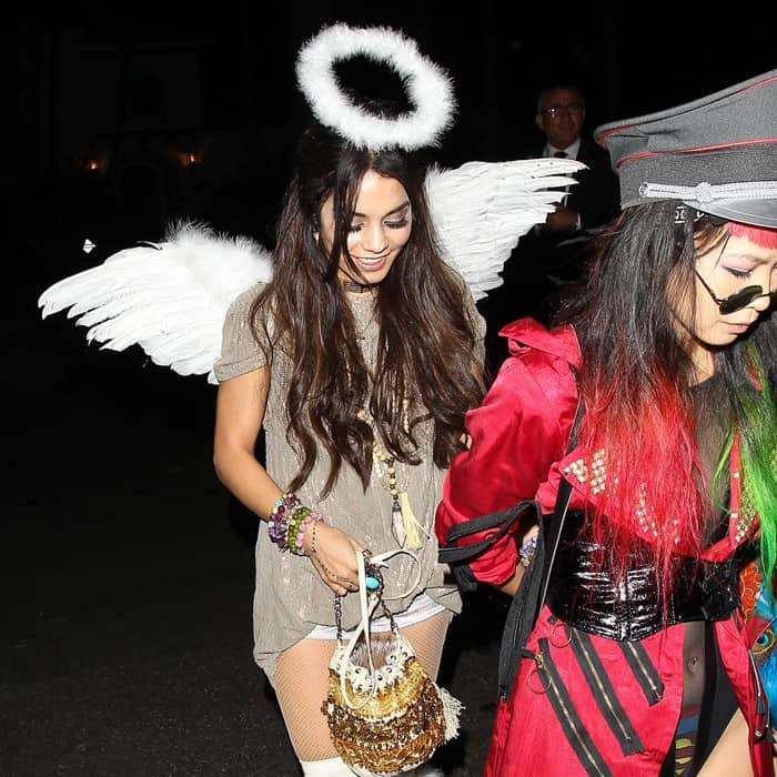 Vanessa Hudgens dazzles in her ethereal angel costume with a halo, wings, fishnet stockings, and a glittery gold purse