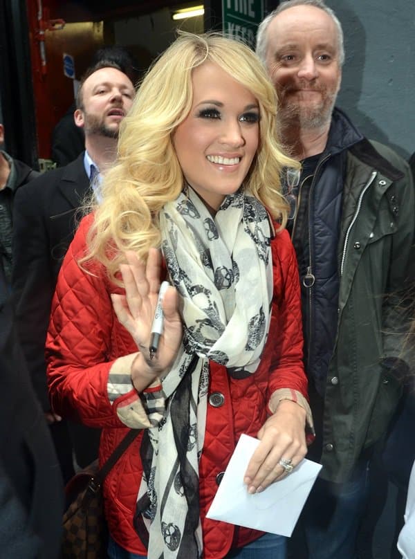 Carrie Underwood wears her classic white McQueen skull scarf with a bright red jacket as she signs autographs for fans while in Dublin, Ireland, on March 14, 2013