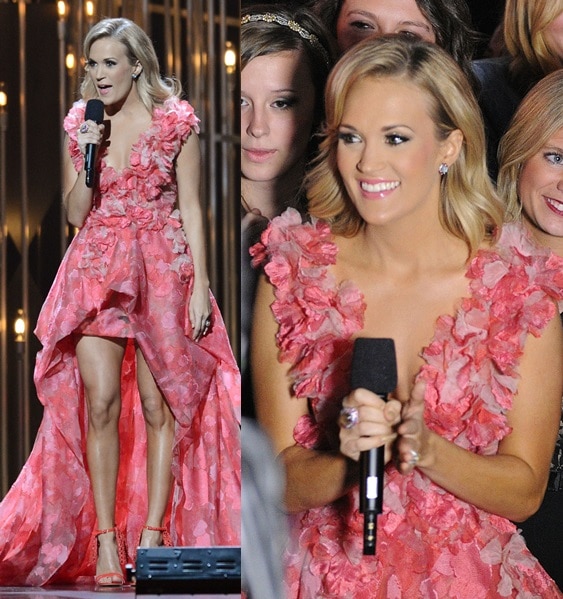 Carrie Underwood clutches her microphone while wearing a pink ruffled gown at the CMAs