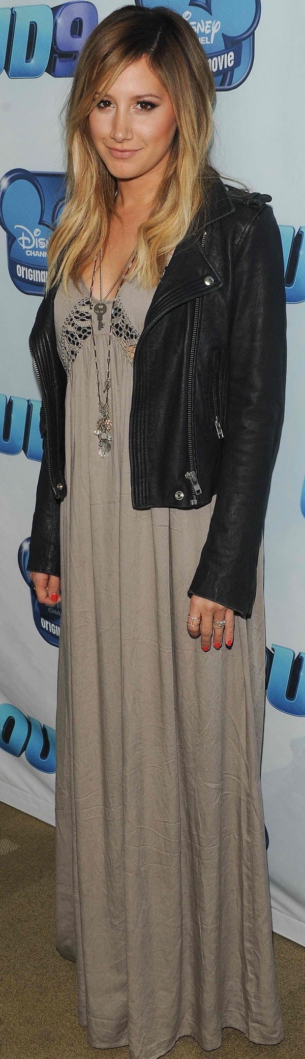 Ashley Tisdale stuns in a taupe maxi dress paired with a black leather jacket, accessorized with layered necklaces