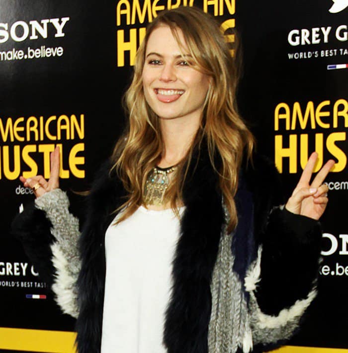 Behati Prinsloo flashes a peace sign from the black carpet of the "American Hustle" screening