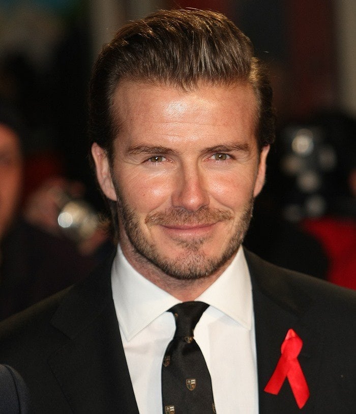 David Beckham looks dapper in a classic black suit with a red awareness ribbon pinned to his lapel
