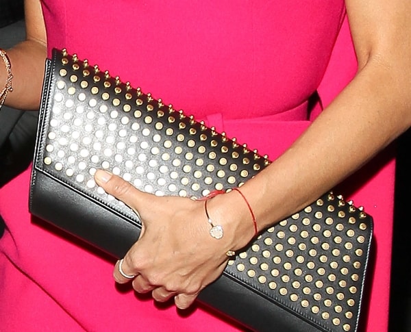 Eva Longoria adds an edgy twist to her chic ensemble with a bold Saint Laurent “Diagonale” clutch, featuring eye-catching gold-tone studs and a sleek black leather finish