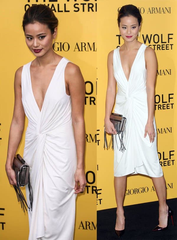 Jamie Chung wearing a white silk dress with a deep V-neckline and a gathered knot detail at the waist, paired with dark burgundy Christian Louboutin pumps and a fringed clutch