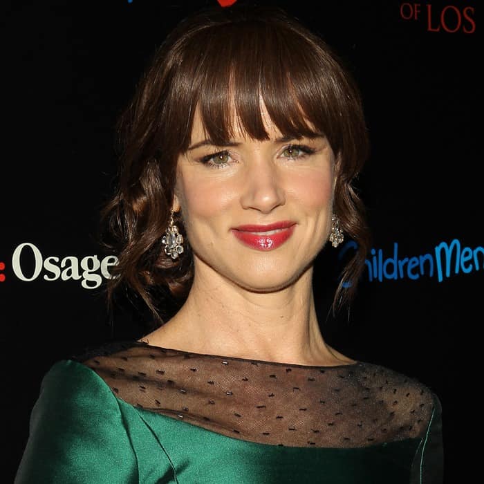 Juliette Lewis completes her elegant look with sparkling drop earrings and a chic emerald green Pamella Roland dress featuring a sheer polka-dot yoke and beaded accents