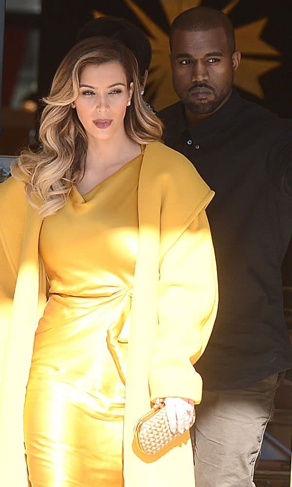 Kim Kardashian steps out with Kanye West, dazzling in a mustard yellow silk dress and matching coat, her look completed with a gold clutch and glamorous waves in her hair