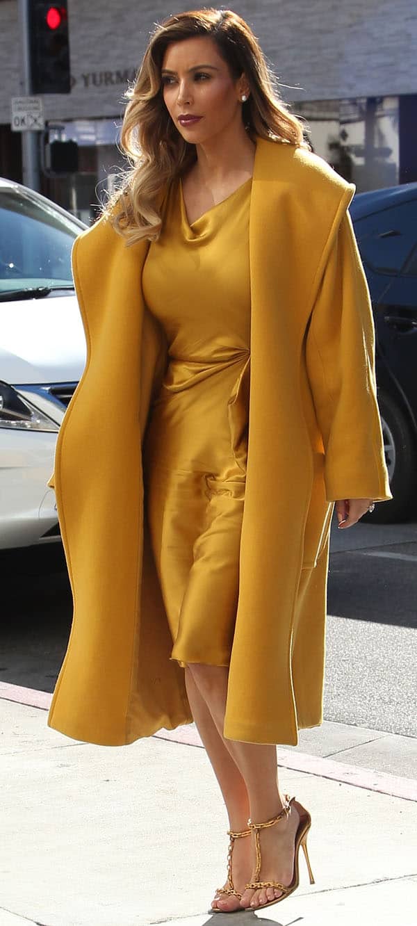 Kim Kardashian wearing a Max Mara coat and mustard yellow silk dress