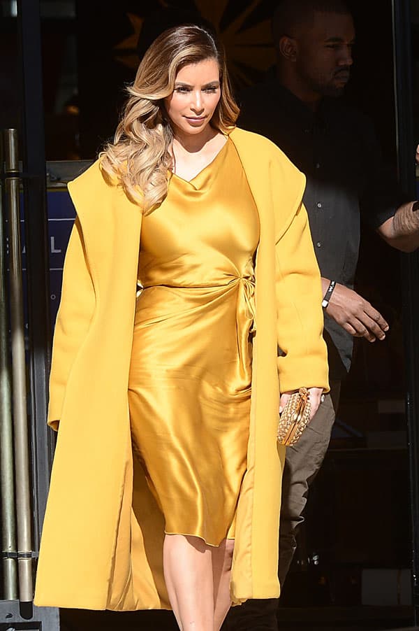Kim Kardashian steps out in a luxurious gold silk dress and matching yellow coat, showcasing her elegant style during a shopping trip