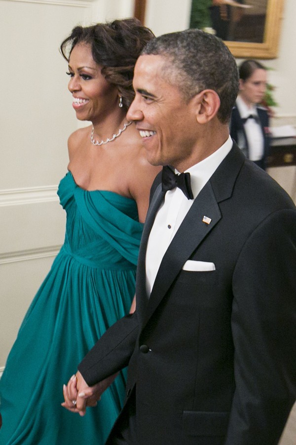First Lady Michelle Obama radiates elegance in an emerald green Marchesa gown as she walks hand-in-hand with President Barack Obama at the 2013 Kennedy Center Honors Gala