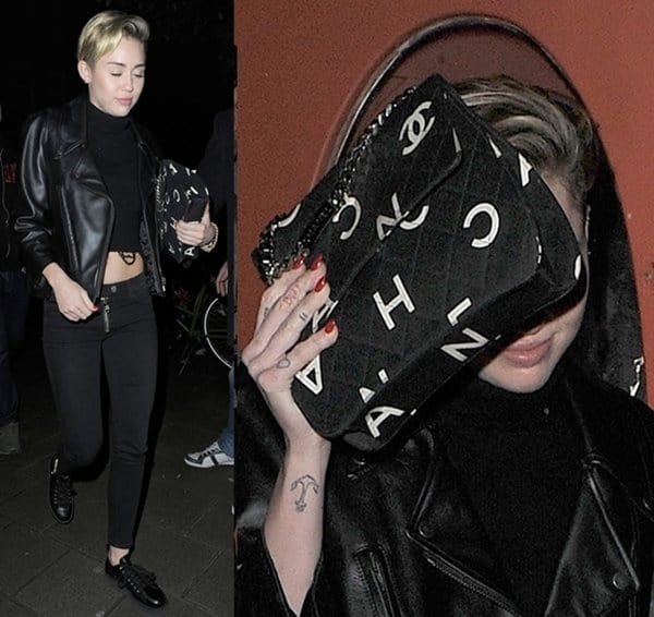 Miley Cyrus keeps it edgy in an all-black leather look, playfully shielding her face with a bold printed Chanel handbag while out in Amsterdam on November 9, 2013