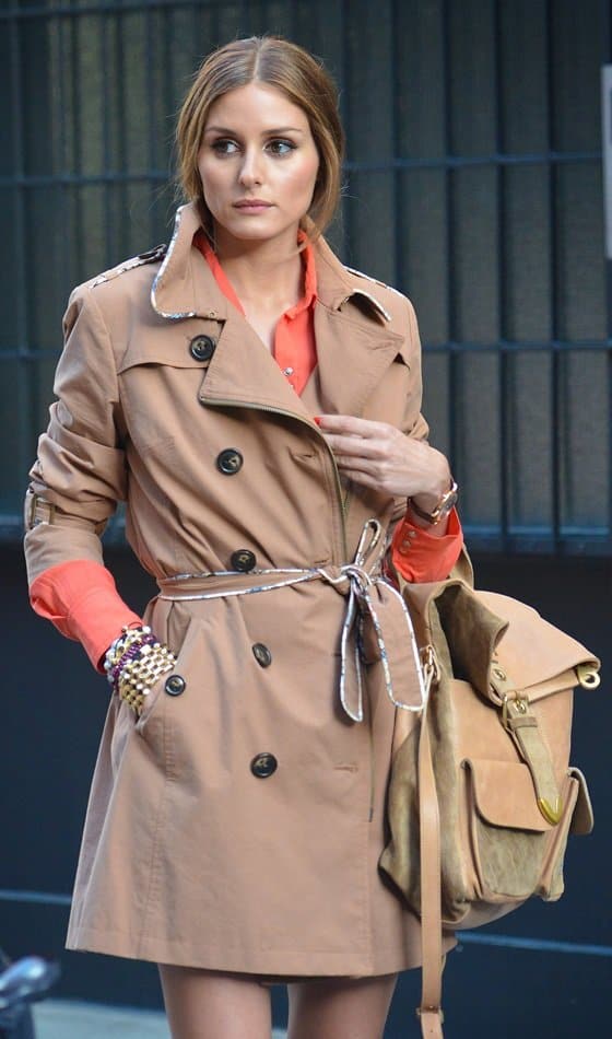 Olivia Palermo exudes effortless sophistication in a tailored trench coat and vibrant coral blouse, accessorized with a chic khaki backpack while out in New York City on June 5, 2013