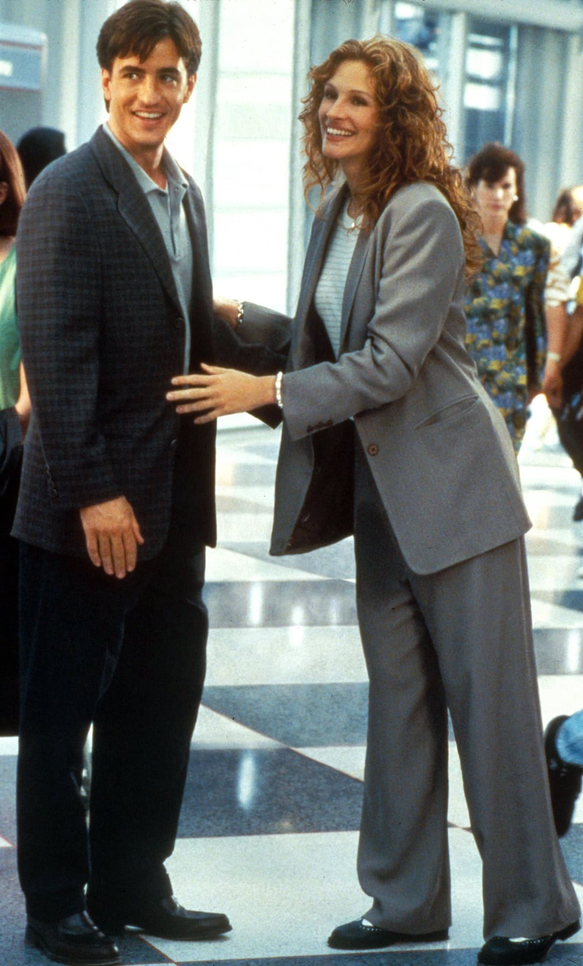 Julia Roberts channels peak ’90s power dressing in a slouchy gray suit and black rounded-toe flats during the unforgettable airport chase scene in My Best Friend’s Wedding