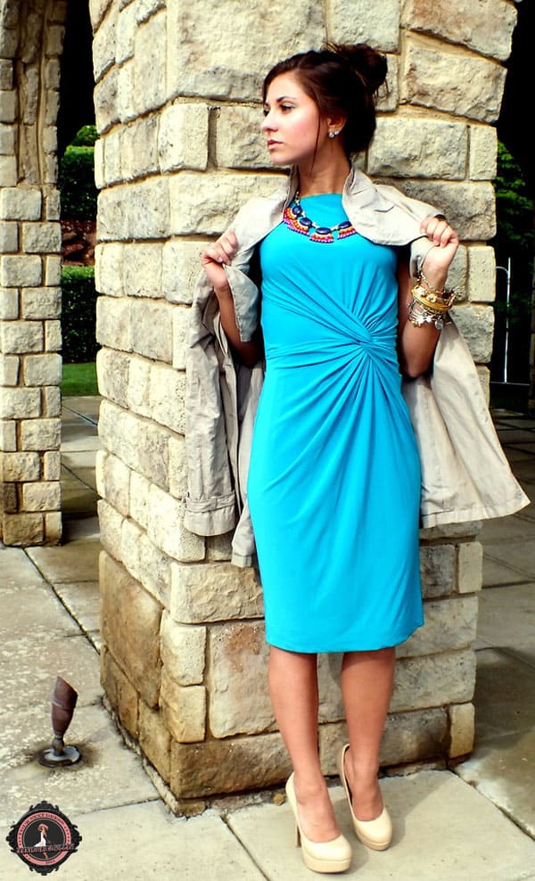 Cara wears a blue knotted dress with a statement necklace
